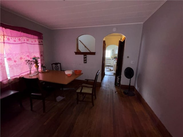 dining space featuring crown molding, wood finished floors, arched walkways, and baseboards