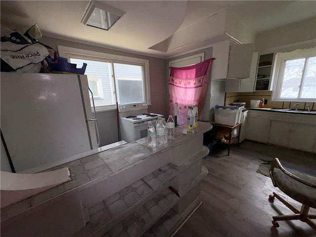 kitchen featuring white appliances, white cabinets, light wood-style floors, and a sink