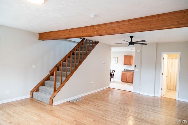 unfurnished living room with light wood-type flooring, stairway, baseboards, and visible vents