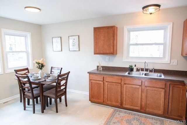 kitchen with dark countertops, visible vents, brown cabinets, and a sink