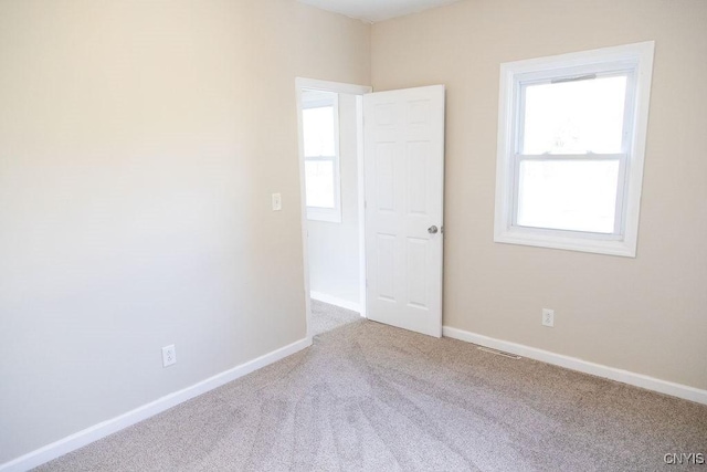 spare room with carpet floors, visible vents, and baseboards