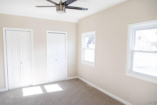 unfurnished bedroom with baseboards, carpet, visible vents, and multiple closets