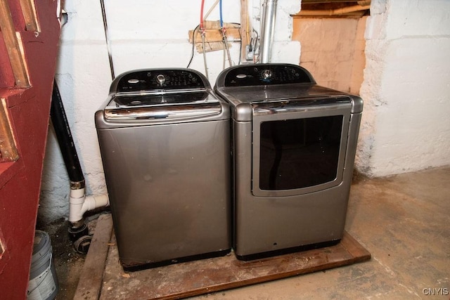 laundry room with concrete block wall, laundry area, and washing machine and clothes dryer