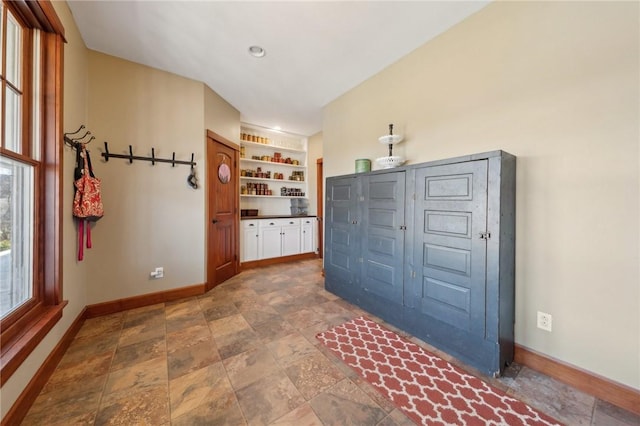 mudroom with built in features, stone finish flooring, and baseboards