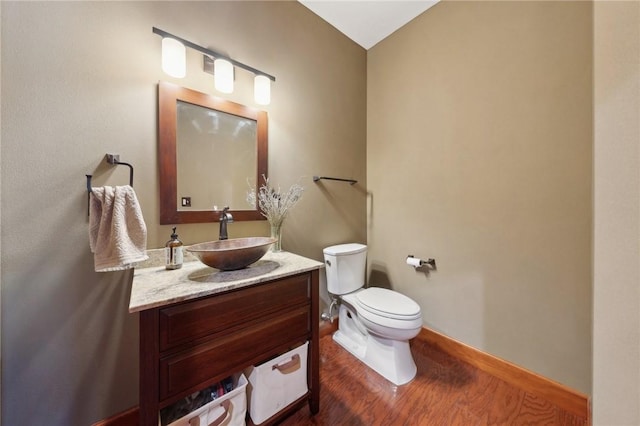 bathroom with toilet, baseboards, wood finished floors, and vanity