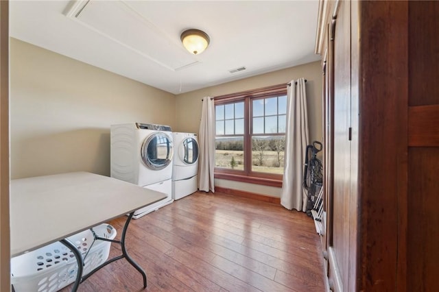 laundry room with laundry area, baseboards, visible vents, hardwood / wood-style flooring, and separate washer and dryer