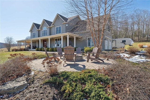 rear view of property featuring covered porch, an outdoor fire pit, and a patio area