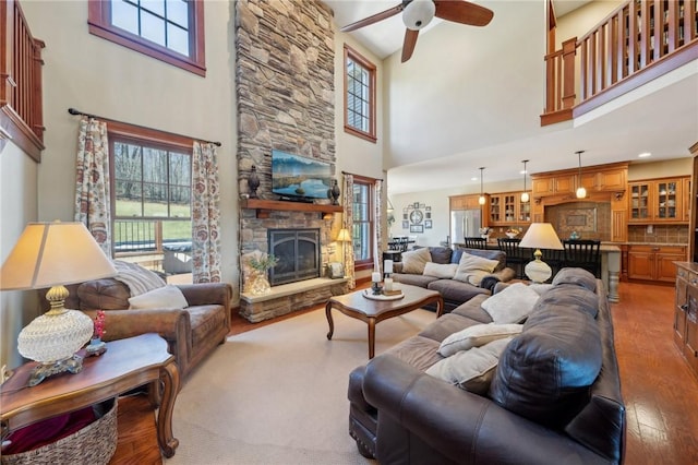 living area featuring a ceiling fan, a wealth of natural light, wood-type flooring, and a fireplace