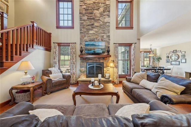 living area with plenty of natural light, a high ceiling, stairway, and a fireplace