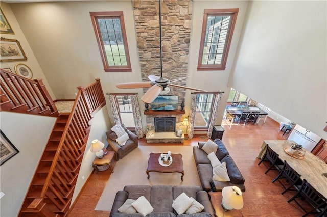 living room featuring wood finished floors, plenty of natural light, a fireplace, and a high ceiling