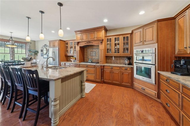 kitchen with stainless steel appliances, brown cabinets, and a sink