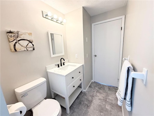 bathroom with vanity, toilet, and a textured ceiling