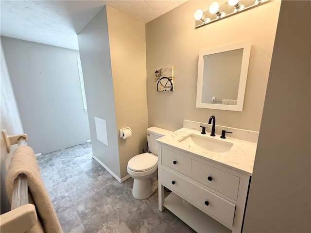 bathroom with toilet, baseboards, a textured ceiling, and vanity