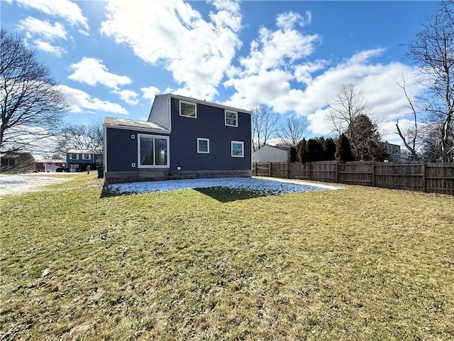 rear view of house featuring fence and a lawn