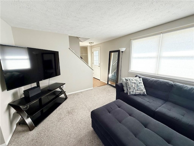 carpeted living area featuring stairs, baseboards, and a textured ceiling