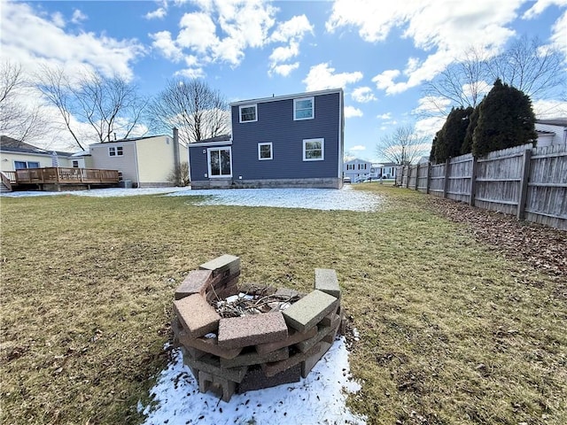 rear view of house with a fire pit, a yard, a deck, and fence