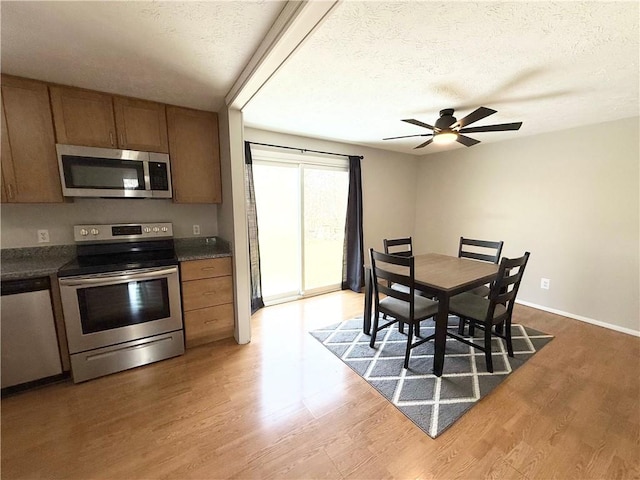 kitchen featuring a textured ceiling, stainless steel appliances, dark countertops, and wood finished floors