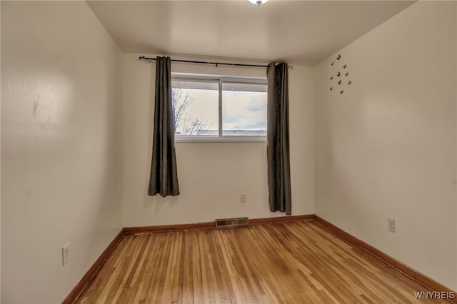 spare room with baseboards, visible vents, and light wood-style floors