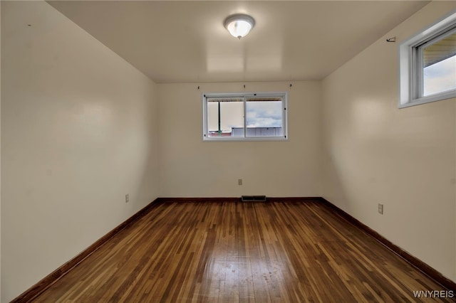 unfurnished room featuring visible vents, baseboards, and dark wood-style flooring