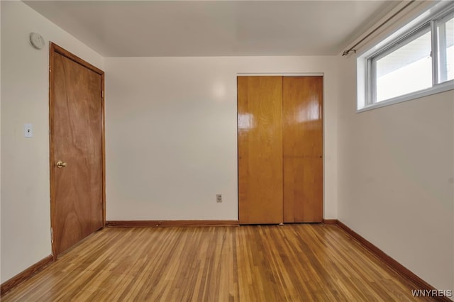 unfurnished bedroom featuring a closet, light wood-style flooring, and baseboards