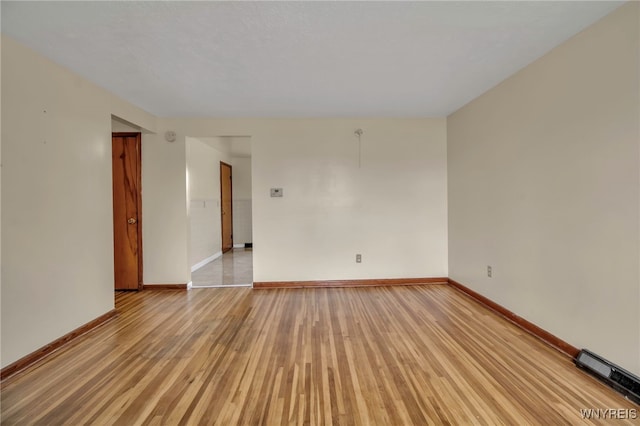 spare room featuring light wood-type flooring, visible vents, and baseboards