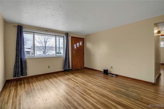 interior space with a textured ceiling, baseboards, and hardwood / wood-style floors