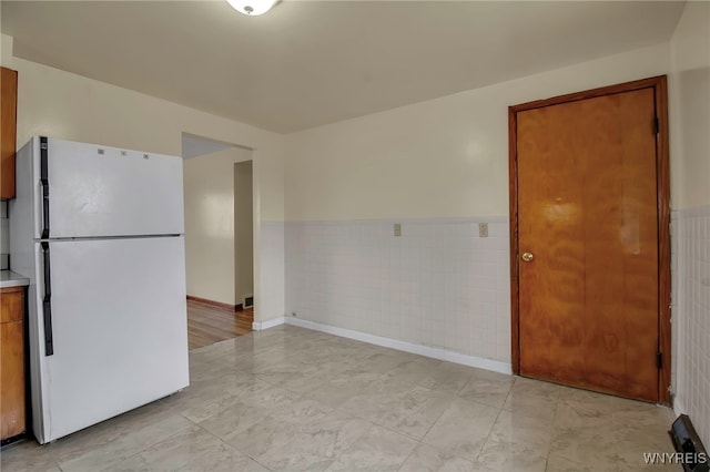 unfurnished room with a wainscoted wall and tile walls