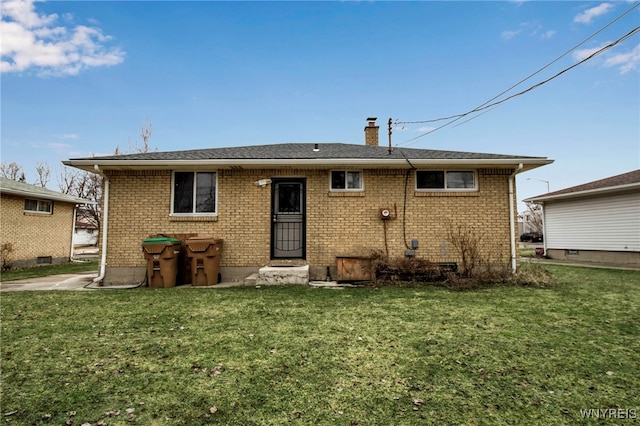 rear view of house with brick siding, a lawn, and a chimney