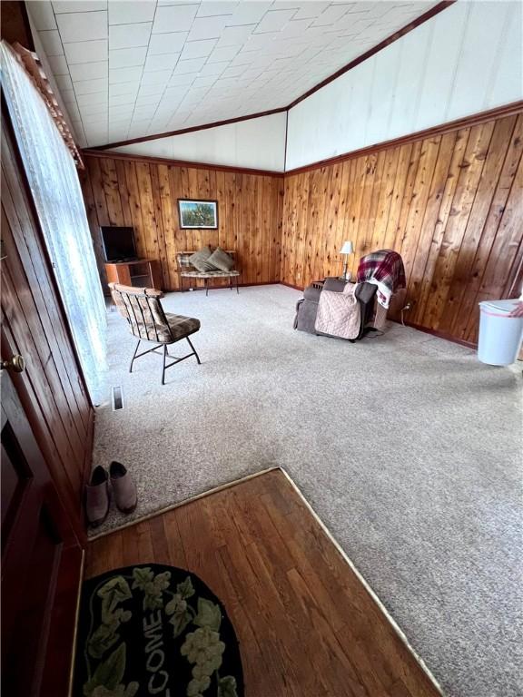 unfurnished room with lofted ceiling, carpet floors, and wood walls