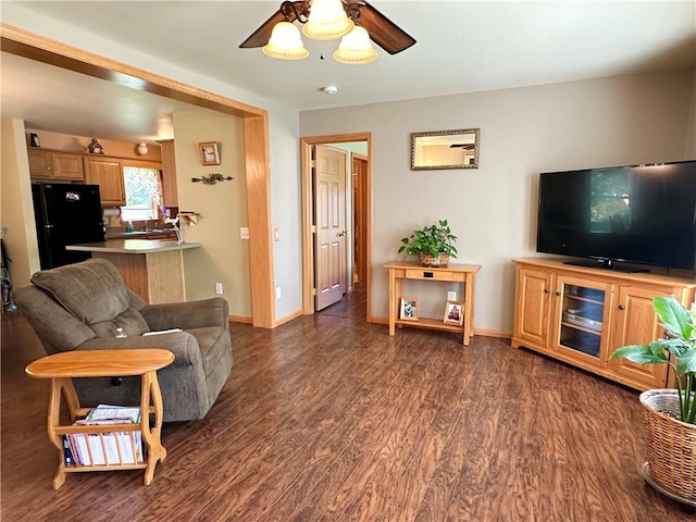 living room with wood finished floors, a ceiling fan, and baseboards