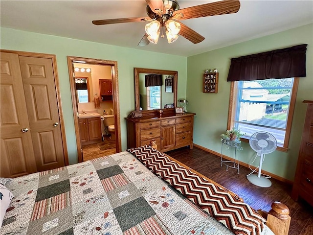 bedroom featuring ceiling fan, wood finished floors, a sink, baseboards, and ensuite bath