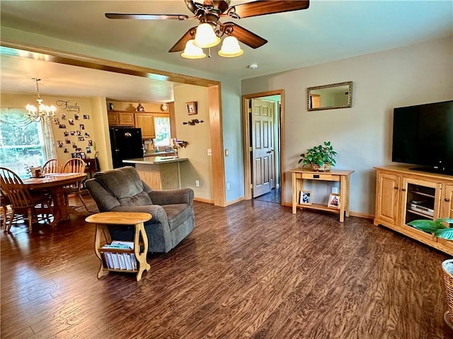 living room with dark wood-style floors, baseboards, and ceiling fan with notable chandelier