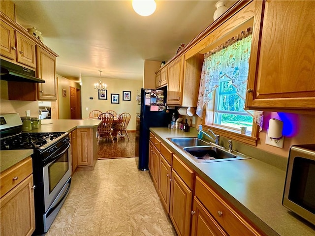 kitchen featuring gas range, freestanding refrigerator, under cabinet range hood, a chandelier, and a sink