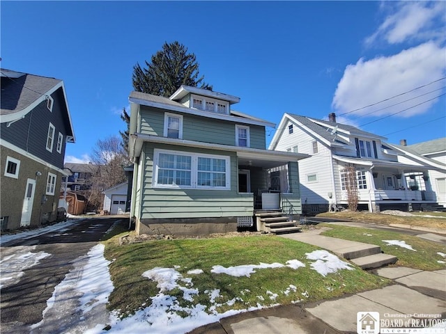 american foursquare style home featuring a porch, an outdoor structure, and aphalt driveway