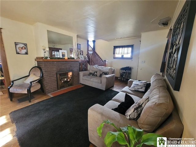 living room featuring stairs, crown molding, a fireplace, and wood finished floors