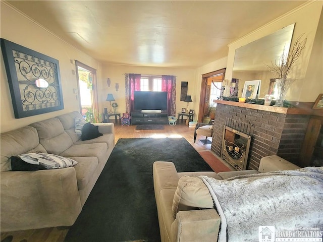 living room featuring a brick fireplace and wood finished floors