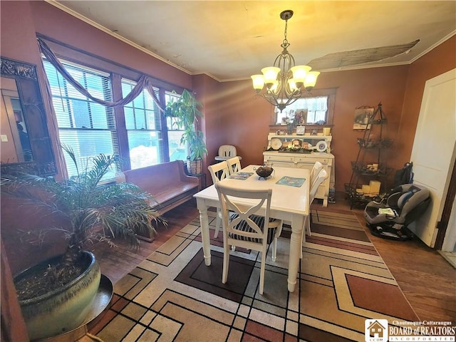 dining space with a notable chandelier, crown molding, and wood finished floors