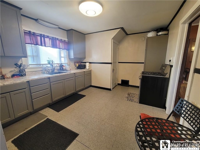 kitchen with a sink, light countertops, gray cabinets, and baseboards