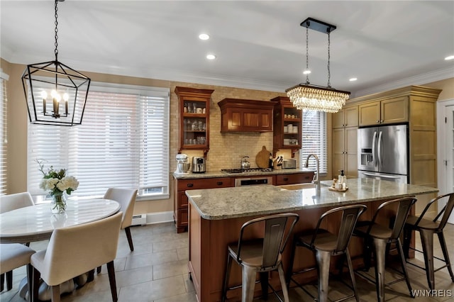 kitchen with appliances with stainless steel finishes, brown cabinetry, a sink, and ornamental molding