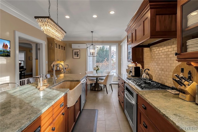 kitchen with brown cabinetry, light stone counters, a notable chandelier, stainless steel appliances, and a sink