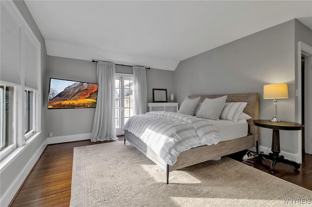 bedroom featuring dark wood-type flooring, vaulted ceiling, and baseboards