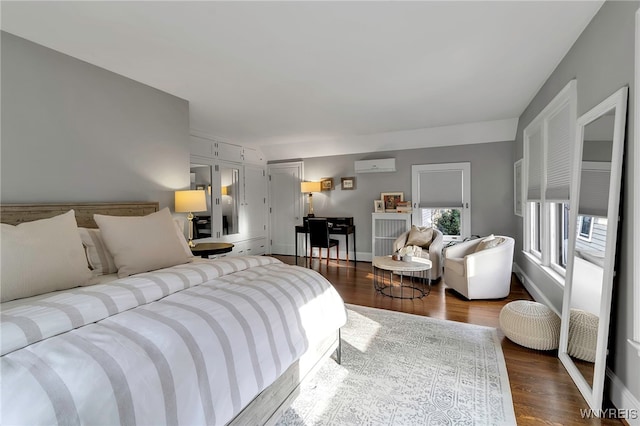 bedroom featuring dark wood-style floors, a wall mounted air conditioner, and baseboards