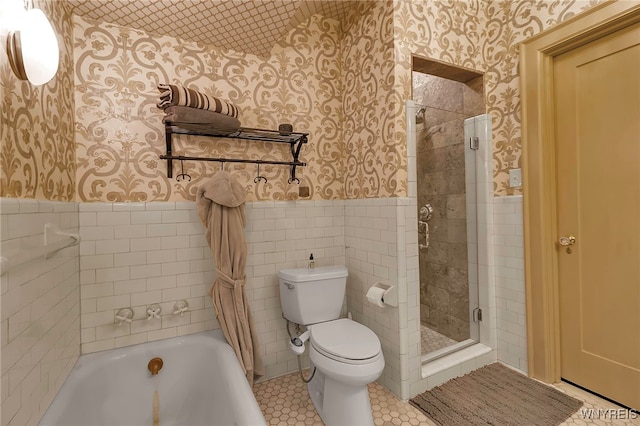 bathroom featuring wallpapered walls, a stall shower, and wainscoting