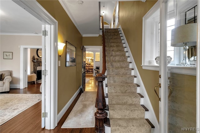 stairs with ornamental molding, baseboards, and wood finished floors