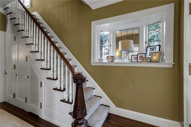 stairway with plenty of natural light, baseboards, and wood finished floors