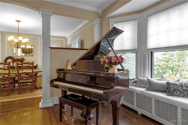 sitting room featuring ornate columns, ornamental molding, wood finished floors, and an inviting chandelier