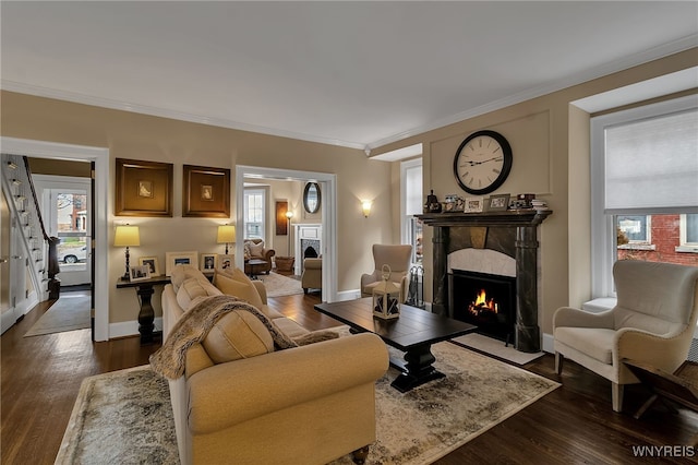 living area featuring ornamental molding, a fireplace, dark wood finished floors, and baseboards