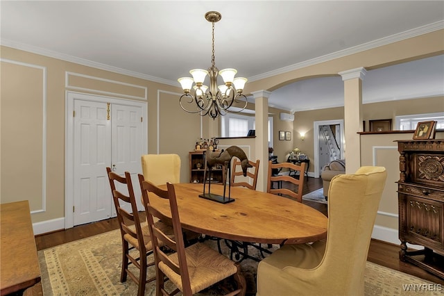 dining room featuring ornate columns, light wood-style flooring, ornamental molding, and arched walkways