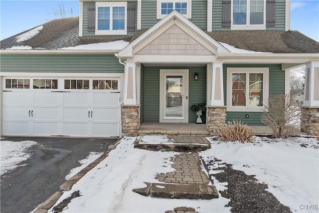 view of front facade featuring aphalt driveway, roof with shingles, a porch, a garage, and stone siding