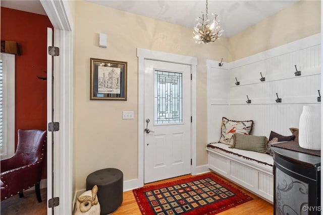 mudroom with baseboards, light wood-style flooring, and an inviting chandelier